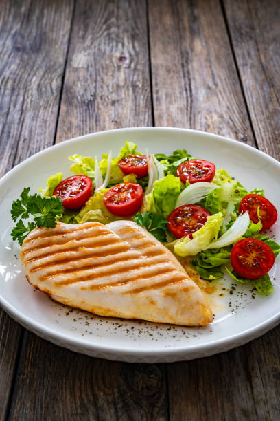 istock Grilled chicken breast with tomatoes and lettuce on wooden table 1939130952
