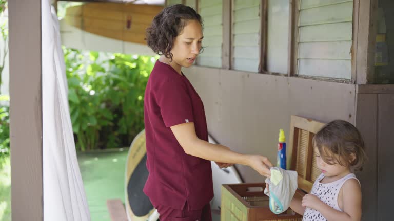 Nurse doing laundry at home with toddler daughter's help