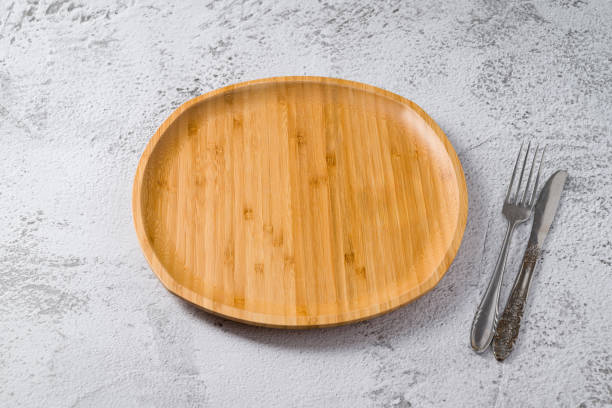 istock Wooden plate, fork and knife on white stone background. handmade kitchen utensils 1939162078
