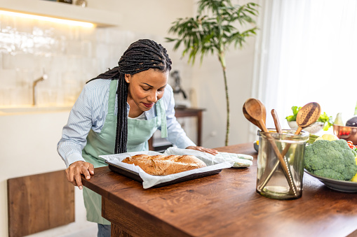 Woman putting home made warm bread on kitchen table