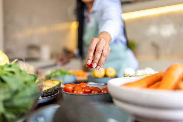 istock Afro-American woman cutting cherry tomato in her kitchen 1939190783