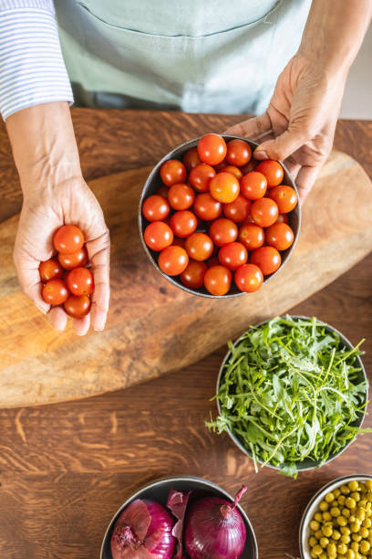 Photo of Afro-American woman with cherry tomato in her kitchen.