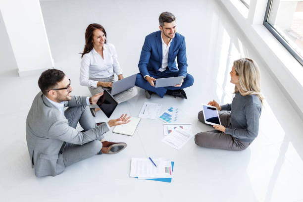 istock Above view of happy entrepreneurs using wireless technology on floor in the office. 1939251597