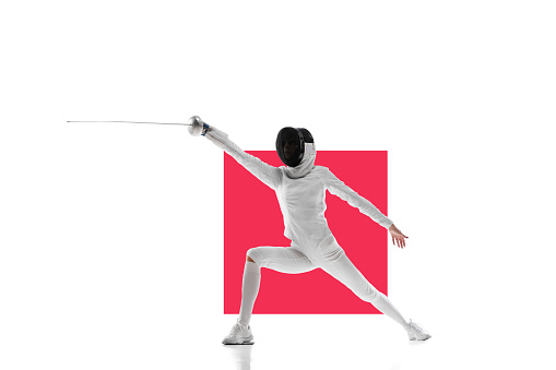 Female fencer in motion, training over white background with red element. Concentrated young woman. Concept of professional sport, competition, championship, hobby. Poster for ad