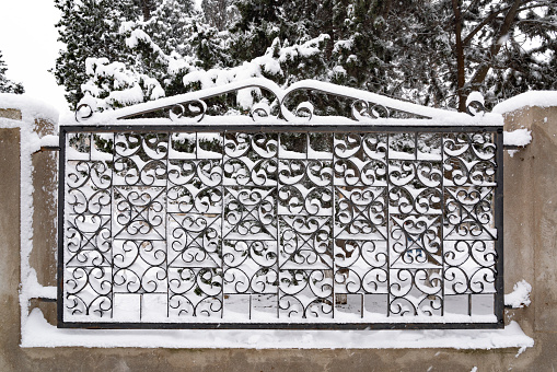 Iron fence of country house after snowfall