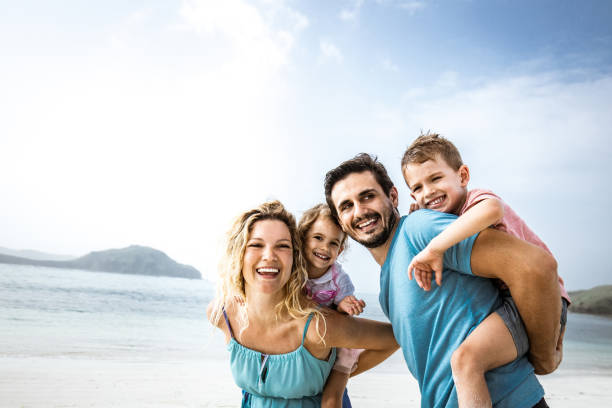 istock Playful family having fun while piggybacking on the beach. 1939284117