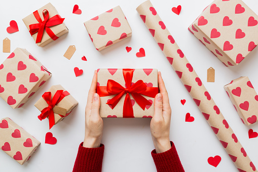 Give a gift on Valentine Day.Valentine gift. Beauty Woman hands holding Gift box with red bow over holiday background.