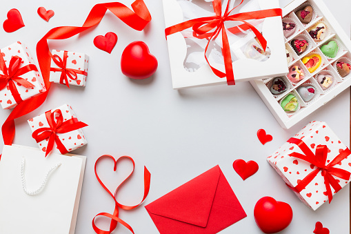 top view photo of st valentine day decor shopping, bag, envelope, gift, box, candy and red heart on colored background with empty space. Frame background.