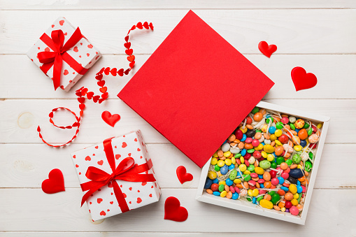 Valentine day composition: sweet candy, with gift boxes with bow and red felt hearts, photo template, background. Top View with copy space.