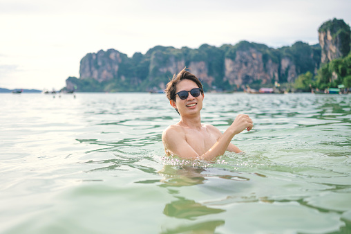 Active lifestyle Solo backpacker relaxing while floating in the ocean swimming with hapimess and joyful moment krabi railay thailand