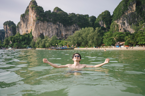 Asian Portrait cheerful man enjoy sunbathing at swimming pool looking at sunset at krabi thailand