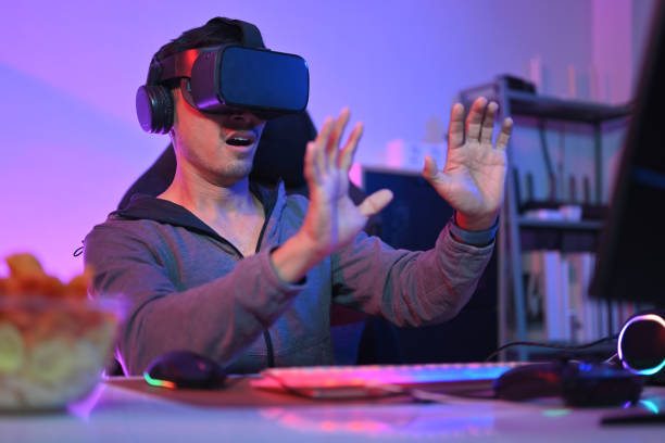 istock Excited man having fun playing video games with virtual reality headset at home 1939331934