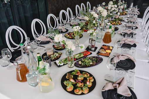 Food and drink on dining table. Plate and glass, luxury rich decor. Wedding set up, dinner table reception on terrace. Serving, setting table in empty backyard. Birthday, baptism, event.