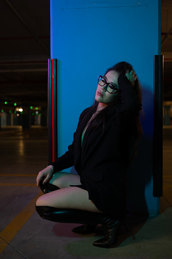 Young attractive model sitting on ground and posing in indoor parking.