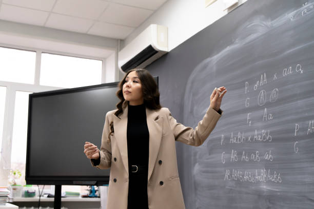 istock female teacher writing biology formulas on a blackboard in classroom 1939377768