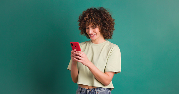 Smiling young female with mobile phone on green background