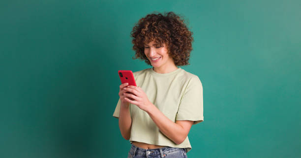 Happy woman with smartphone green studio stock photo