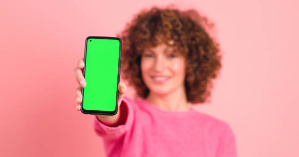 Happy woman showing mobile phone with chromakey in studio stock photo
