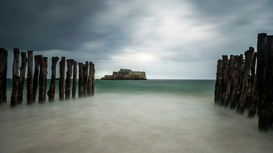 The beach and Fort National during high tide in Saint Malo (Bretagne, France) on a stormy, cloudy day in summer, long exposure