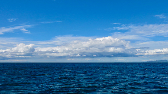View of the sea surface, small waves and white cumulus clouds above the horizon. Sea background.