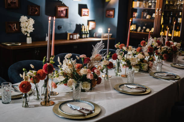 Serving, setting table. Festive dinner table is served dishes and cutlery and decorated with flowers and greenery, candles. Birthday celebration. Family holidays in modern dining restaurant.