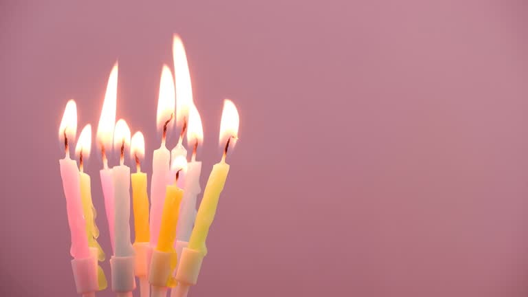 Birthday candles burning on pink background, copy space for text.