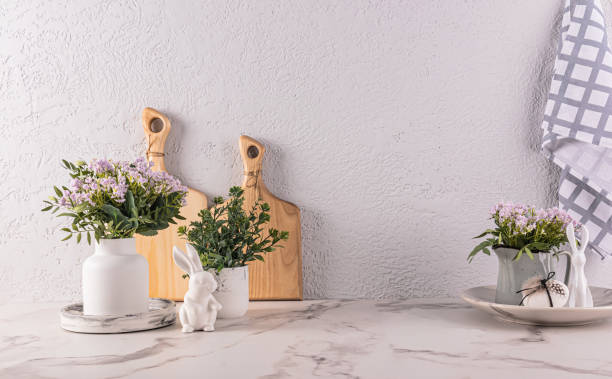 istock Spring flowers in vase and jug on kitchen countertop with Easter decorations. cutting boards, towels. Easter bunny figurines. 1939464058