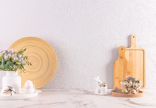 Festive decorations of kitchen stone countertop for Easter day. wooden kitchen utensils, ceramic bunny, vase of flowers. Eco-friendly kitchen