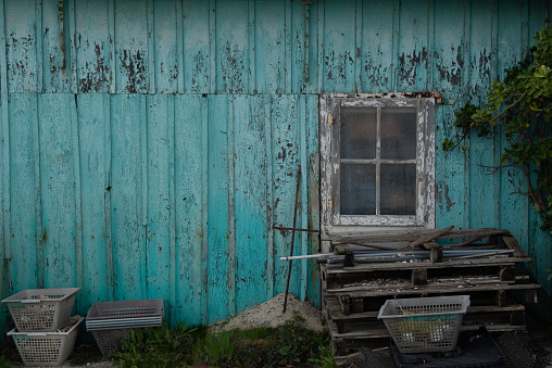 Facade of blue cabin clad in wood worn by time.