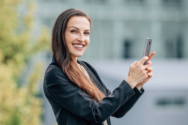 istock business woman with mobile phone outdoors, smiling 1939500839