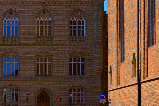 Facade of the historic building with windows and red brick walls. Ancient architecture, church. Poland, Torun, August 2023.
