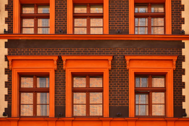 Facade of the historic building with windows, orange frames and a brown brick wall. Ancient architecture. Torun, Poland, August 2023
