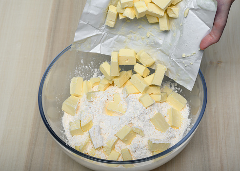 Throw the sliced ​​stick of butter straight from the packaging into the bowl with flour close up, isolated