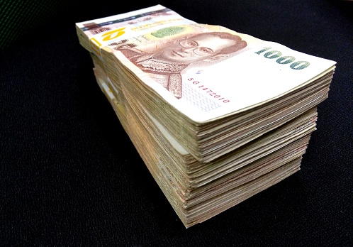 A big stack of Thai baht cash money bank notes on black background.