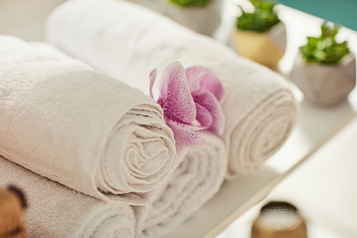 Flowers, salon and towel in spa decorations for zen, calm and peace for massage treatment. Beauty, luxury and closeup of cosmetics, aromatherapy and aesthetic for wellness, dermatology and skincare