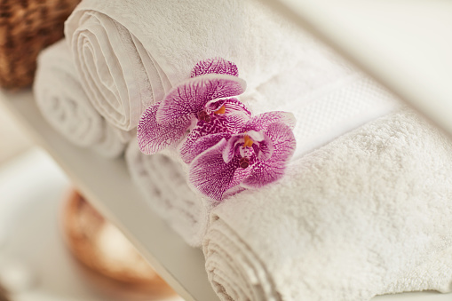 Flowers, salon and towel in spa aesthetic for zen, calm and peace for massage treatment. Beauty, luxury and closeup of cosmetics, aromatherapy and decorations for wellness, dermatology and skincare
