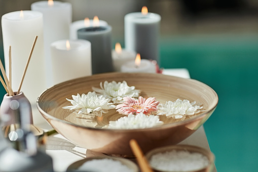 Flowers, candle and spa aesthetic with water for zen, calm and peace for massage, treatment and beauty. Salon, luxury and essential oils, bowl and aromatherapy for wellness, dermatology and skincare