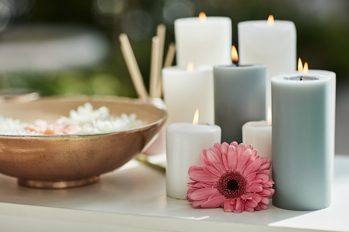 Flower, candles and ambience in spa to relax for luxury wellness at hotel, lodge or resort accommodation. Massage, hospitality and aromatherapy with still life objects in salon for stress relief