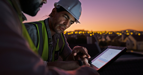 Construction worker men, tablet and roof at sunset, discussion or click in planning, development or expansion. Engineer, people and digital touchscreen for chart, information or data analysis in city