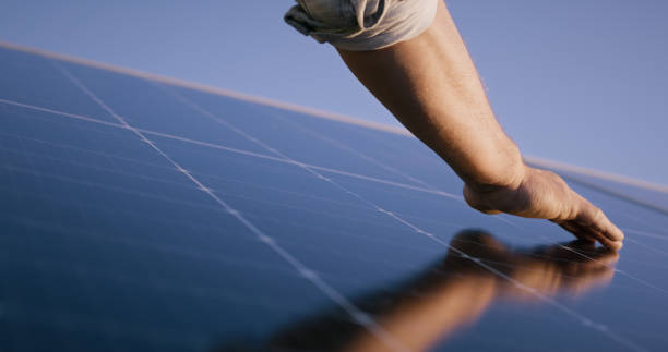istock Hand, closeup and solar panel with roof, construction or inspection for sustainability with touch. Electrician, grid and person for photovoltaic tech on rooftop, dust or dirt for power with ecology 1939503145