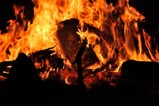 Amidst a campfire's flickering dance in Kfardebian, Lebanon, burning wood ignites a vibrant spectrum from deep blacks to radiant oranges. The flames, chaotic yet mesmerizing, form an intricate canvas, painting a mesmerizing display of elemental fervor.