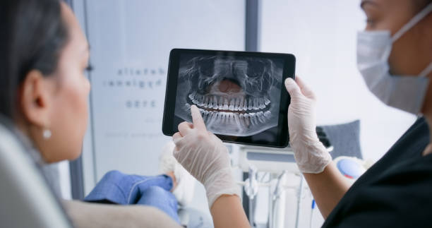 hands, tablet and teeth xray, dentist and patient with dental surgery and health, people and orthodontics at clinic. healthcare, wellness and digital scan of mouth on screen with cavity or gingivitis - dentist surgery dental hygiene using voice imagens e fotografias de stock