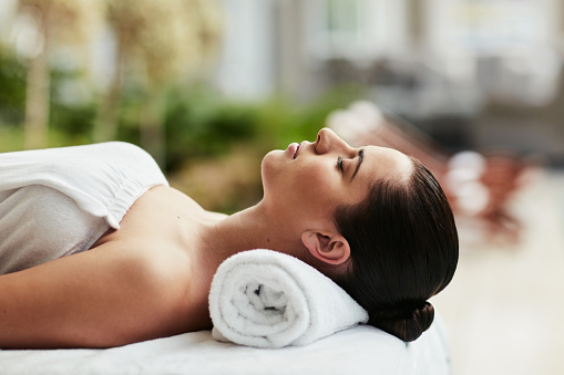 Relax, towel and woman at luxury spa for massage, reiki service or aromatherapy for holistic treatment. Self care, peace and zen, girl on bed for facial wellness and alternative skincare at hotel.