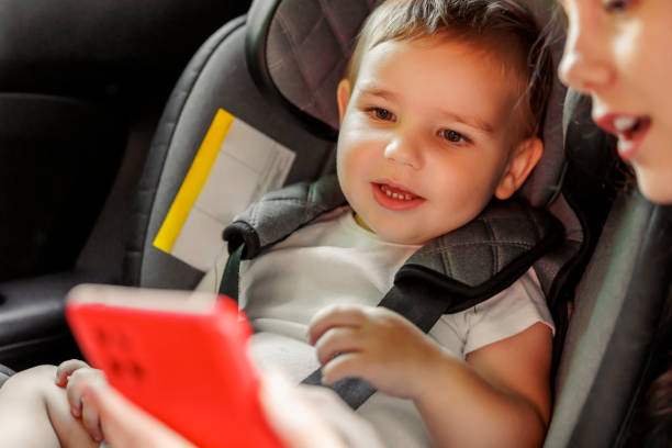 istock Mother using smart phone playing cartoons to baby boy while riding in car 1939517819