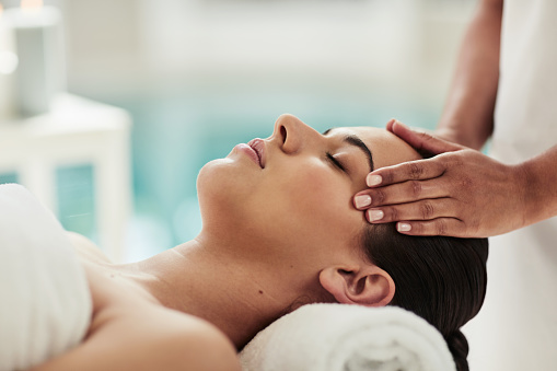 Relax, hotel and woman at spa for massage, reiki service or aromatherapy for holistic treatment. Luxury self care, peace and zen, face of girl on bed for facial wellness and alternative skincare.