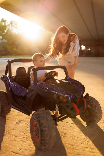 istock Mother having fun assisting toddler son while driving battery powered toy car 1939519456