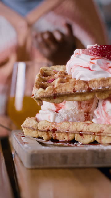 Breakfast, waffle and closeup at coffee shop with food and dessert at a restaurant with cream. Strawberry, hands and waiter person with pancakes, plate and catering to a table in a gourmet bakery