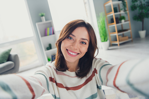 Portrait of friendly cheerful girl toothy smile make selfie recording video modern spacious house inside.