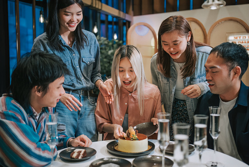 Asian Chinese friends celebrating birthday cutting birthday cake sharing
