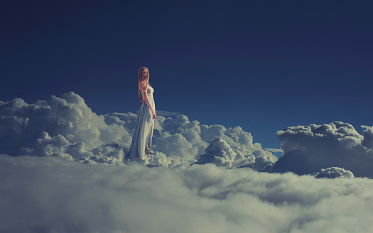 Little girl sitting on a cloud and reading a book up in the sky